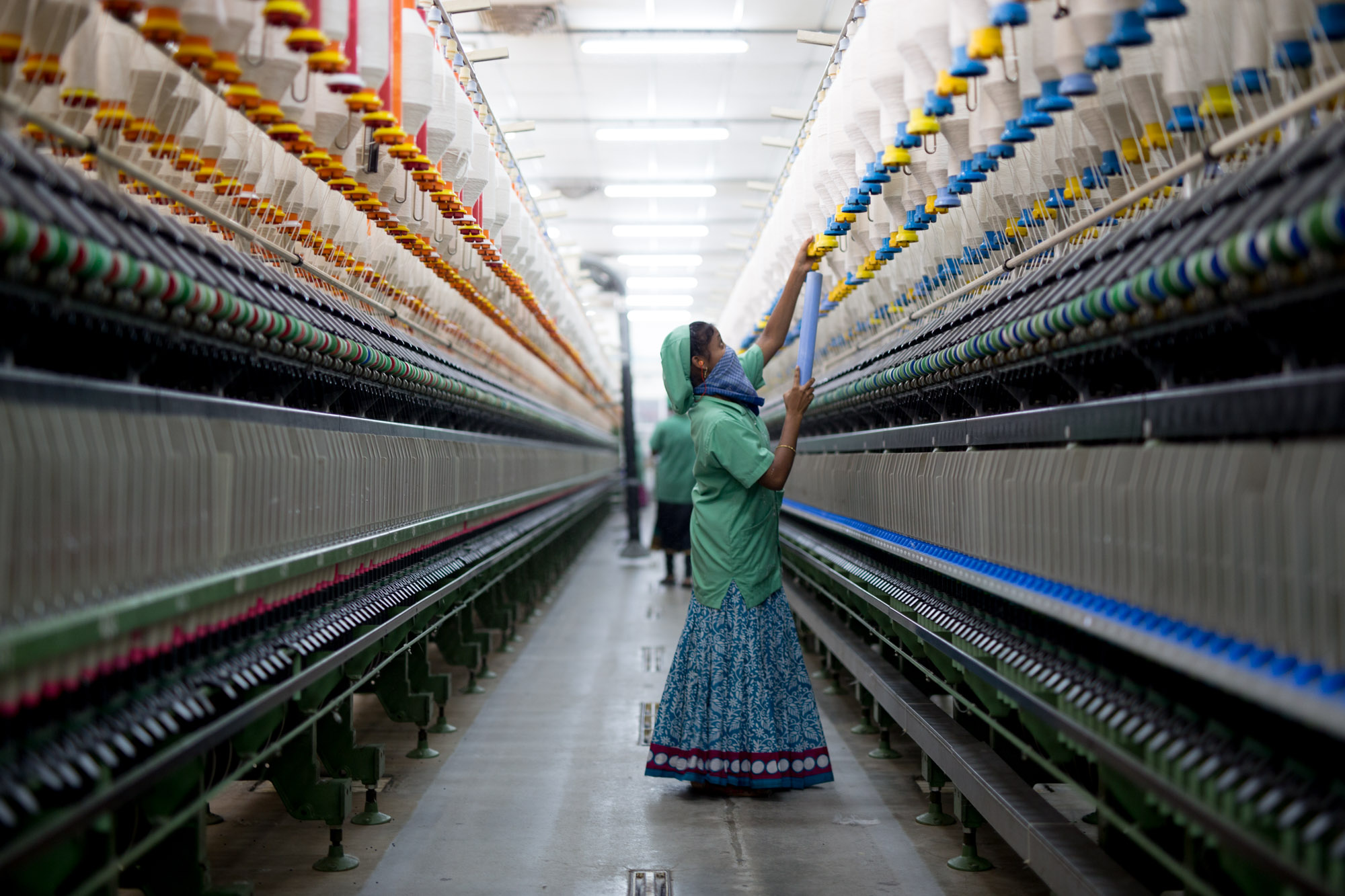 Une femme travaille dans un immense atelier de confection.