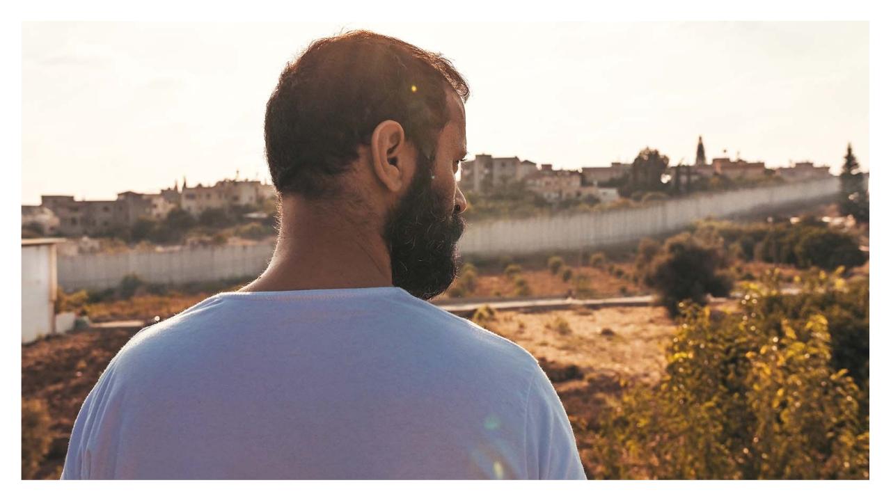un homme de dos, marche en direction du mur séparant Israël de la Cisjordanie.