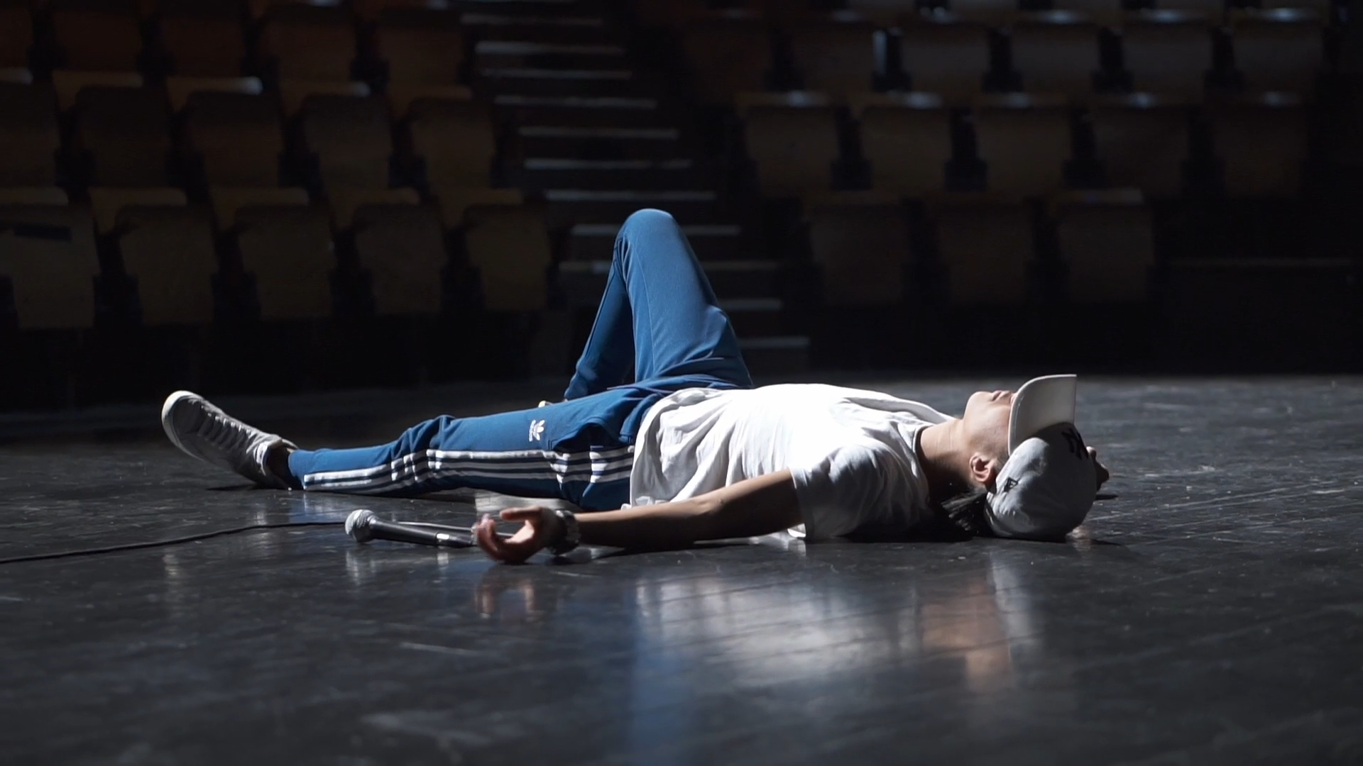 Image du film montrant un jeune couché sur la scène d'un théâtre.