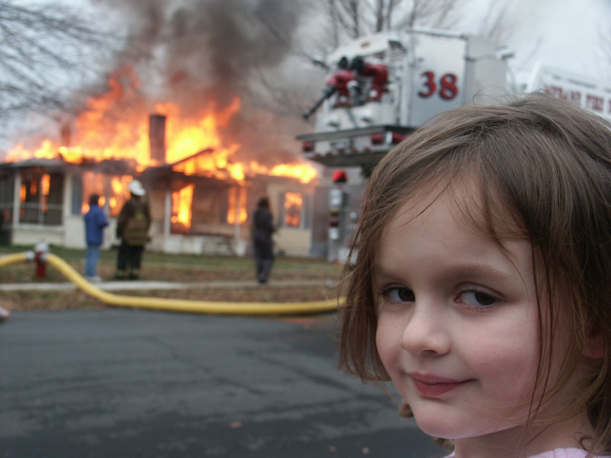 Fillette souriant devant une maison en feu.