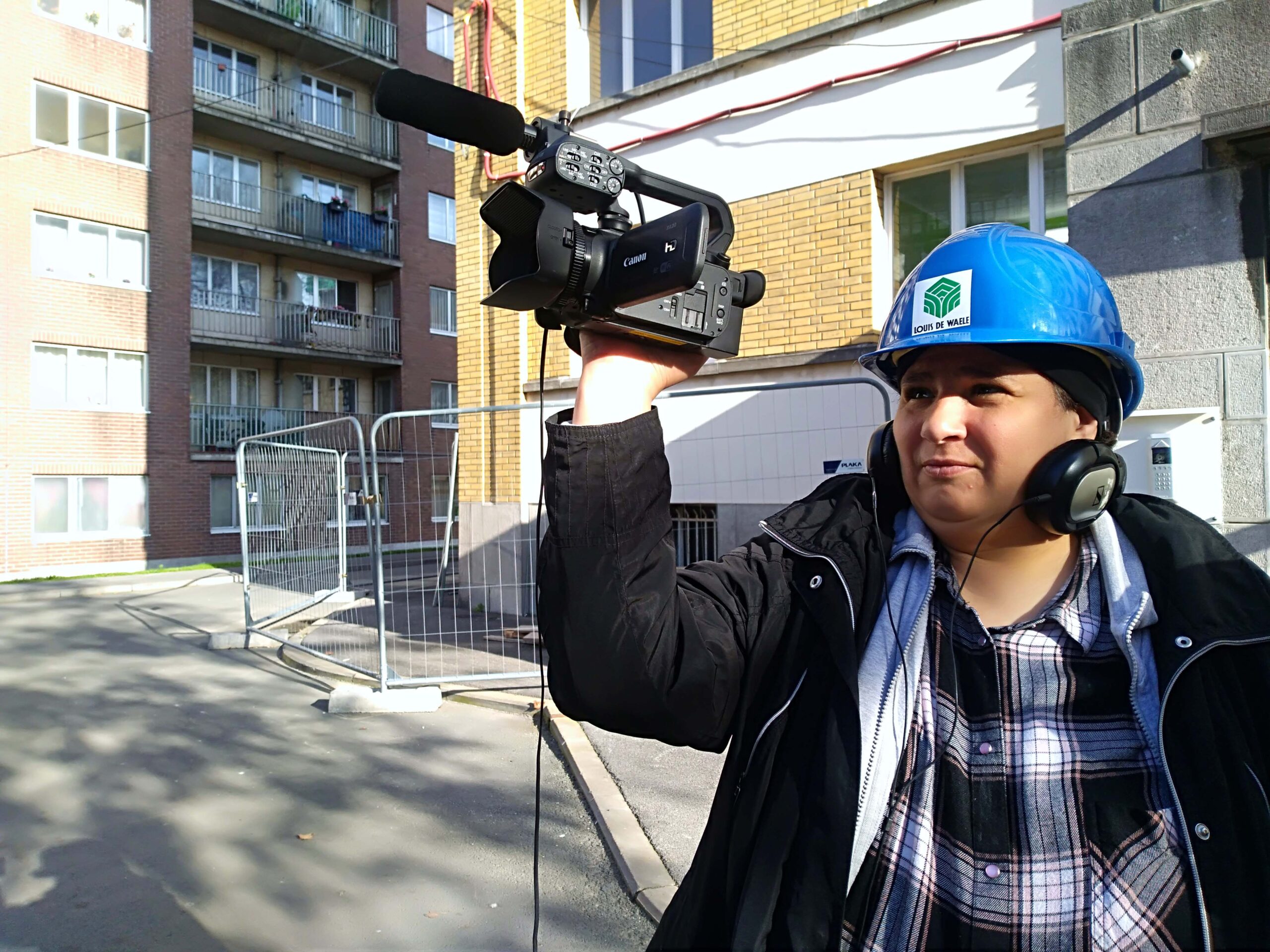 Cameraman en casque bleu filmant en extérieur.